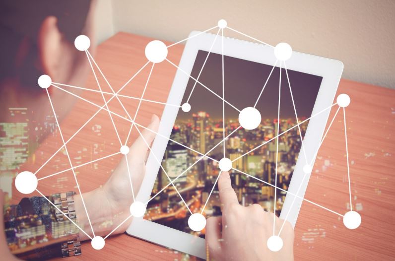 Personne utilisant une tablette affichant une ville connectée