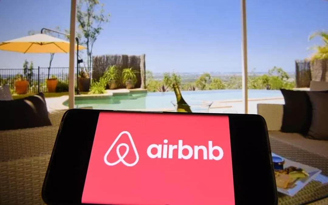 Logo airbnb sur tablette devant piscine d'une villa