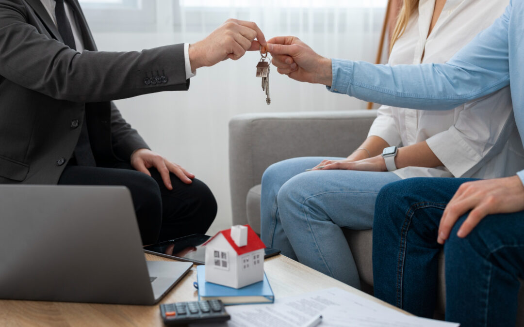 Un agent immobilier en costume remet les clés d'un logement à un couple assis sur un canapé