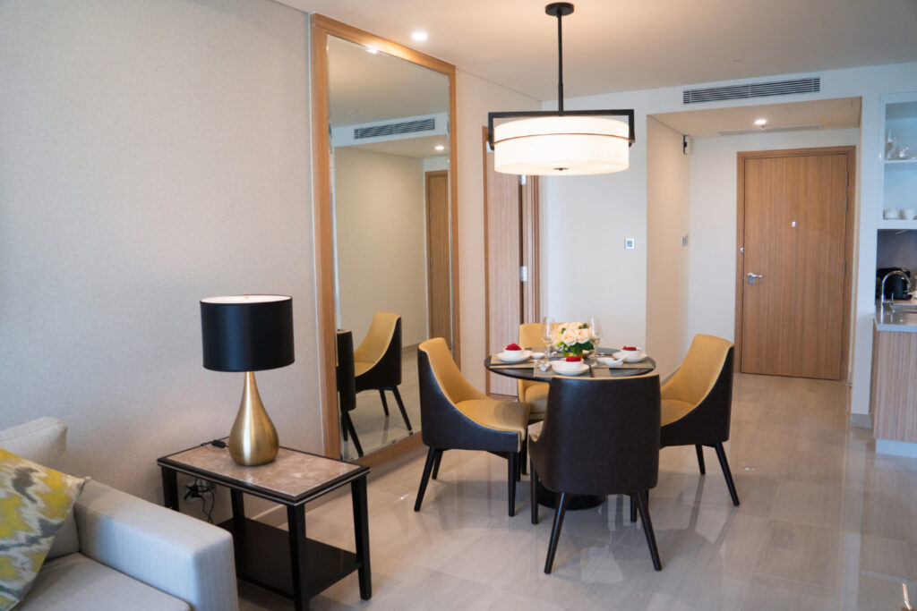 Un intérieur d'appartement moderne et lumineux avec une table à manger dressée et des chaises élégantes.